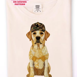 Op de afbeelding: Gevouwen crèmekleurig T-shirt met een illustratie van een Labrador Retriever met een camouflage pet. De hond heeft een lichaam van patchwork in gele en bruine tinten. Het shirt heeft de tekst "NOT A CUTTING OR SEWING PATTERN" en "DIGITAL DOWNLOAD - NOT A PHYSICAL ITEM".
