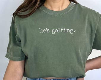 Camiseta Comfort Colors "Ele está jogando golfe", camiseta para esposa/mãe de jogador de golfe