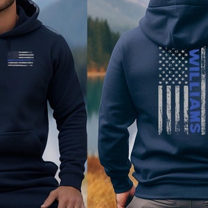 May include: A navy blue hoodie with a thin blue line American flag on the front and a larger version of the flag with the name "WILLIAMS" on the back.