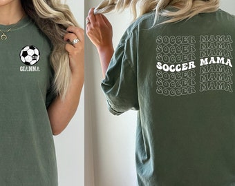 Könnte beinhalten: Ein moosgrünes T-Shirt mit einem Fußball-Motiv und dem Text "GIANNA" auf der Vorderseite. Die Rückseite des Shirts trägt den Text "SOCCER MAMA" fünfmal wiederholt.
