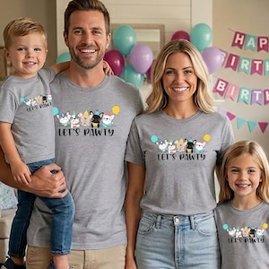 Pode incluir: Uma fam&iacute;lia de quatro pessoas usando camisetas cinza combinando com um design "Let's Pawty" com cachorros de desenho animado e bal&otilde;es. O fundo inclui bal&otilde;es e uma faixa de anivers&aacute;rio.