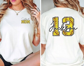May include: White t-shirt with the text "Softball Mom" on the front and a softball-shaped number "13" with the text "Jackson" on the back.
