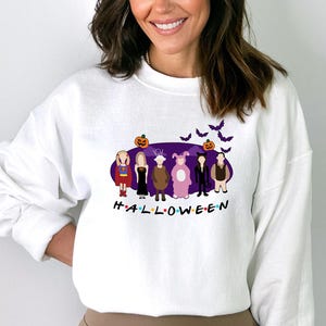 May include: White sweatshirt featuring a purple graphic of the characters from the TV show "Friends" dressed in Halloween costumes. The graphic includes the text "H.A.L.L.O.W.E.E.N."