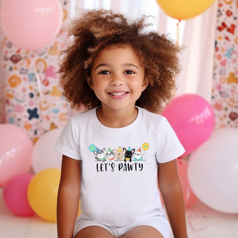 May include: A white t-shirt with a graphic of five dogs wearing party hats and holding balloons. The text "Let's Pawty" is printed below the dogs.
