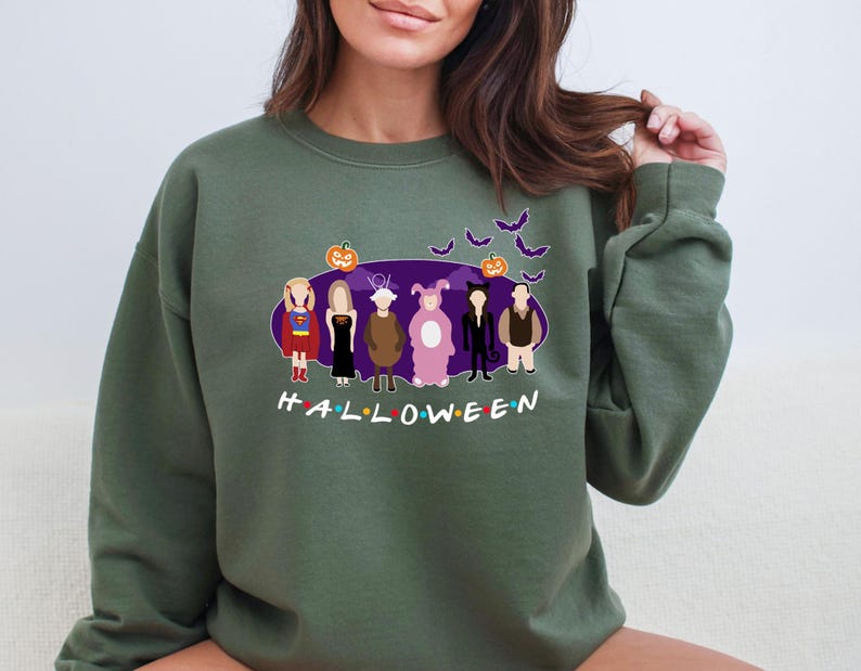 May include: A green sweatshirt featuring a graphic print of the characters from the TV show "Friends" dressed in Halloween costumes. The text "HALLOWEEN" is printed below the characters.