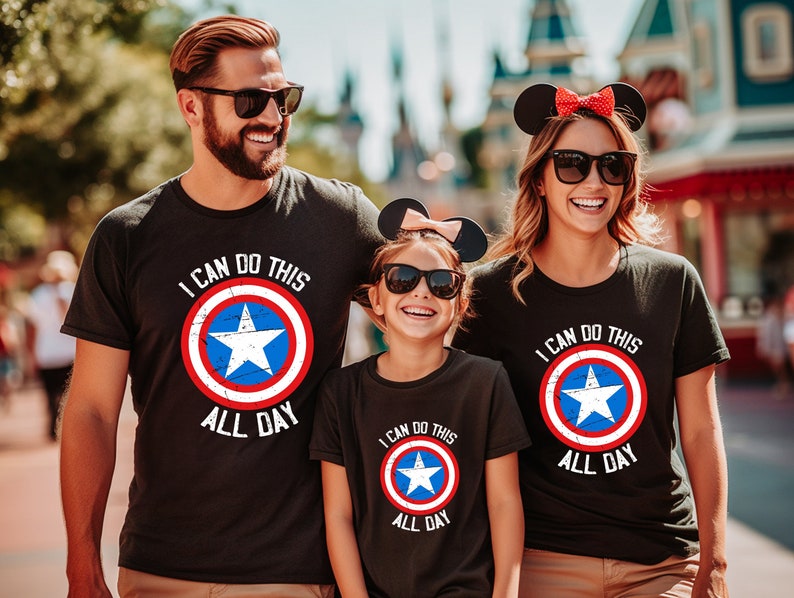 Puede incluir: Una familia de tres personas con camisetas negras con un gr&aacute;fico de escudo de Capit&aacute;n Am&eacute;rica rojo, blanco y azul y el texto "Puedo hacer esto todo el d&iacute;a".