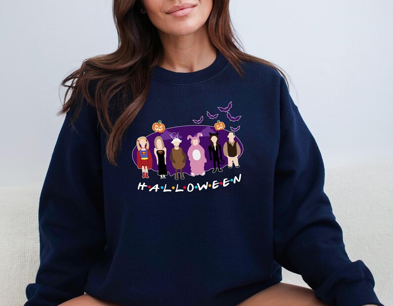 May include: A navy blue sweatshirt featuring a graphic of six cartoon characters dressed in Halloween costumes. The characters are standing in front of a purple background with bats and a pumpkin. The text "HALLOWEEN" is printed below the characters.