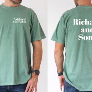 May include: A green t-shirt with the text "Ashford Construction" on the front and "Richard and Sons" on the back.