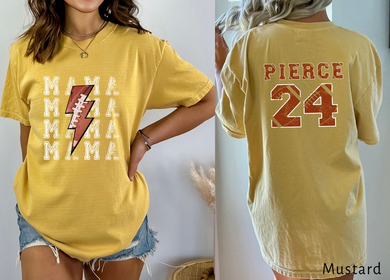 May include: A mustard yellow t-shirt with a football graphic and the text "MAMA" repeated five times on the front. The back of the shirt has the text "PIERCE 24" in red and white.