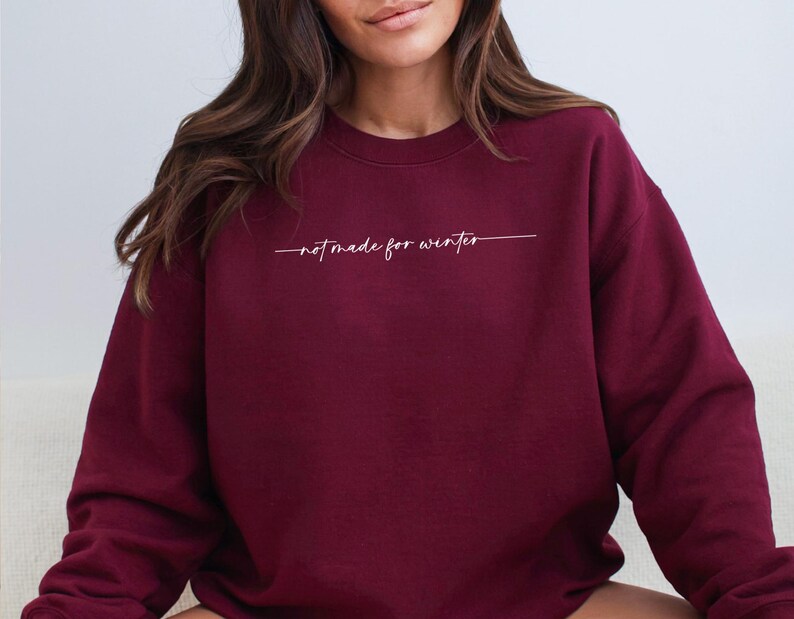 May include: Burgundy sweatshirt with the text "not made for winter" in white lettering.