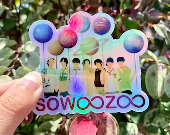 May include: A holographic sticker featuring a group of seven people standing in front of a rainbow background with planets and stars. The sticker has the text "SO WOO ZOO ∞" at the bottom.