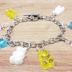 May include: A silver chain bracelet with seven gummy bear charms in various colors, including pink, blue, yellow, and white.