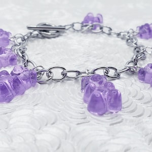 May include: A silver chain bracelet with multiple purple gummy bear charms.