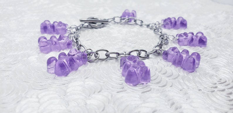 May include: A silver chain bracelet with multiple purple gummy bear charms.