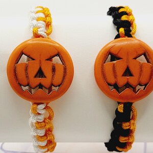 May include: Two Halloween themed bracelets with orange pumpkin charms. One bracelet has white and orange string, the other has black and orange string.