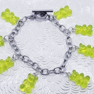 May include: A silver chain bracelet with multiple green gummy bear charms.