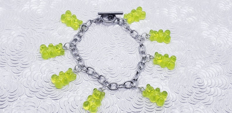 May include: A silver chain bracelet with multiple green gummy bear charms.