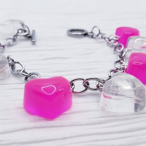 May include: A silver chain bracelet with alternating clear and pink heart-shaped charms.