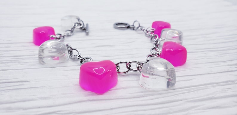May include: A silver chain bracelet with alternating clear and pink heart-shaped charms.