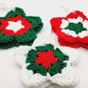 May include: Three crocheted star ornaments in red, white, and green. The stars are layered with different colors, creating a festive design.