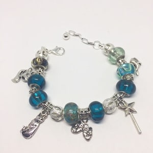 Può includere: Un braccialetto con ciondoli in argento con perline di vetro blu turchese, ciondoli in argento e una catena in argento. I ciondoli includono una nota musicale, una stella, una scarpa e una bacchetta.