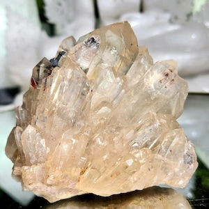 Könnte beinhalten: Ein Cluster aus klaren Quarzkristallen mit einer hellbraunen Färbung. Die Kristalle sind in einer spitzen, stacheligen Formation angeordnet.