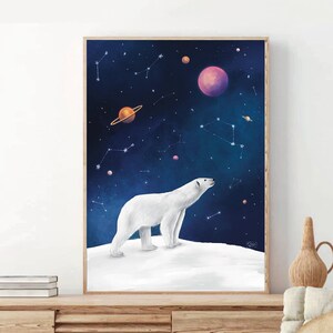 K&ouml;nnte beinhalten: Gerahmter Kunstdruck mit einem wei&szlig;en Eisb&auml;ren, der auf einer schneebedeckten Oberfl&auml;che steht und in einen Sternenhimmel blickt. Das Kunstwerk zeigt Planeten und Sternbilder in Lila, Orange und Blau. Der Druck ist in einem Holzrahmen.