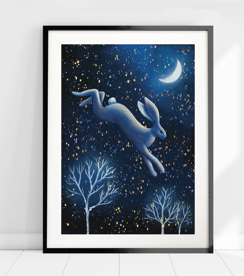 Puede incluir: Una liebre azul salta a trav&eacute;s de un cielo nocturno estrellado con una luna creciente en la esquina superior derecha. La liebre se recorta contra un fondo azul oscuro con estrellas doradas brillantes. Dos &aacute;rboles desnudos est&aacute;n en primer plano.