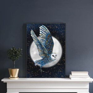 May include: A blue and gold owl with white feathers flies in front of a full moon against a dark blue background with gold glitter stars.