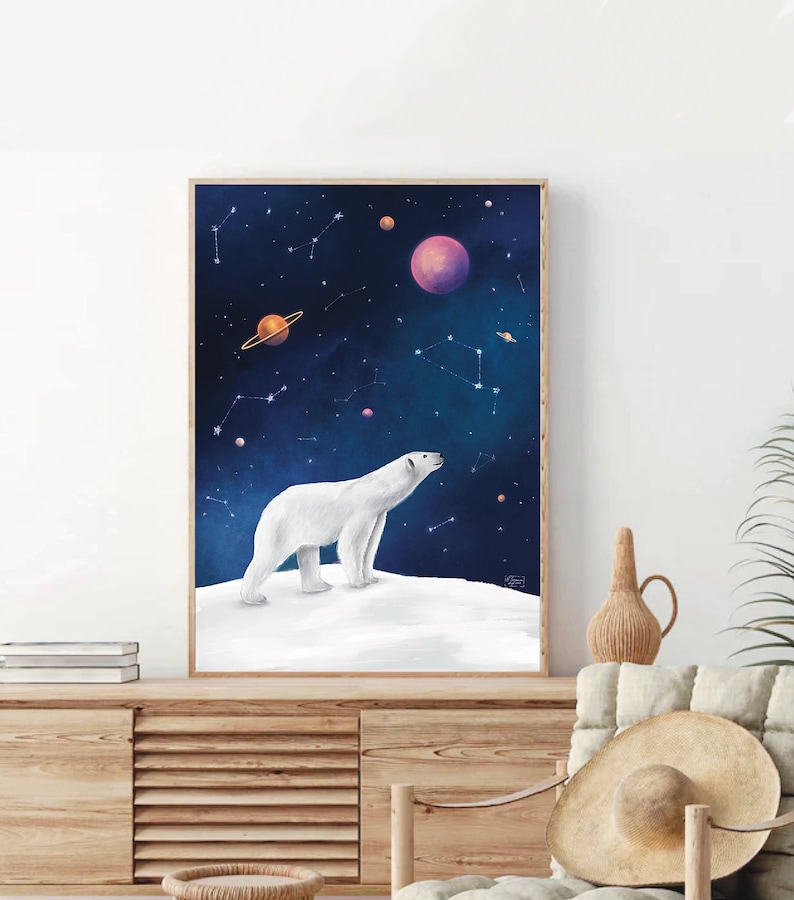 K&ouml;nnte beinhalten: Gerahmter Kunstdruck mit einem wei&szlig;en Eisb&auml;ren, der auf einer schneebedeckten Oberfl&auml;che steht und in einen Sternenhimmel blickt. Das Kunstwerk zeigt Planeten und Sternbilder in Lila, Orange und Blau. Der Druck ist in einem Holzrahmen.