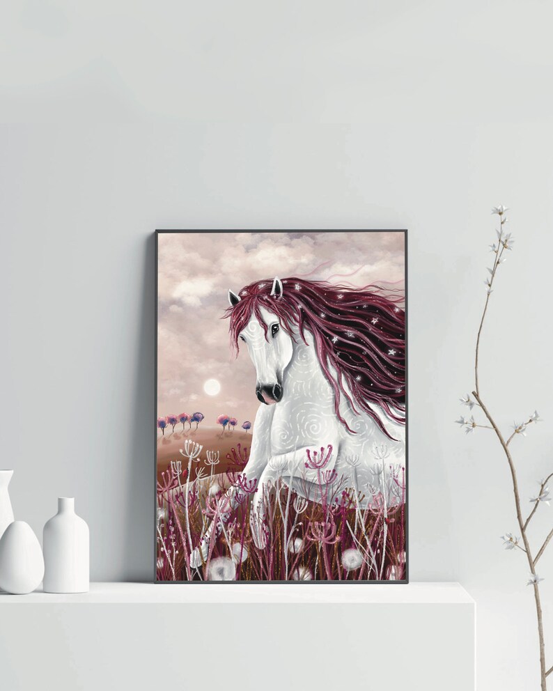May include: A white horse with a long, flowing mane of pink and white hair stands in a field of pink wildflowers. The horse has a white face with a black nose and black eyes. The horse is looking to the left of the image. The background is a soft pink and white sky.