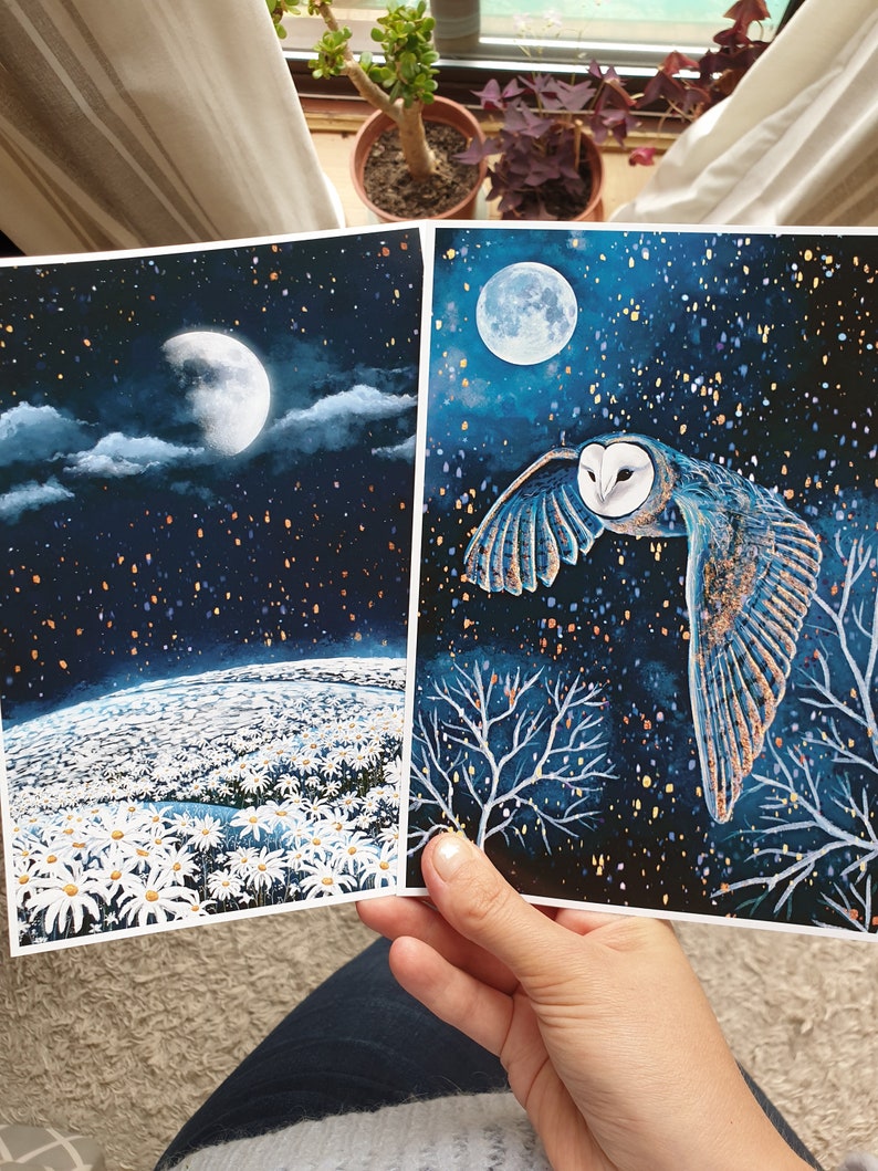 Puede incluir: Dos tarjetas impresas con un tema de cielo nocturno. La primera tarjeta muestra un campo de margaritas blancas bajo una luna creciente y un cielo estrellado. La segunda tarjeta muestra un b&uacute;ho chico volando frente a una luna llena y un cielo estrellado.
