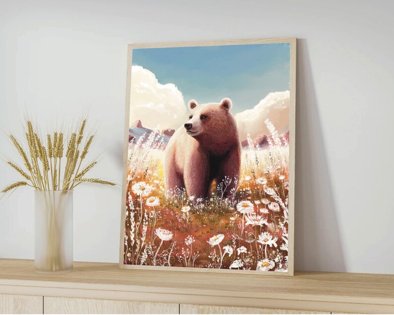 May include: A framed art print featuring a brown bear standing in a field of white wildflowers. The bear is the focal point, set against a backdrop of a blue sky and fluffy clouds. The artwork has a soft, painterly style.