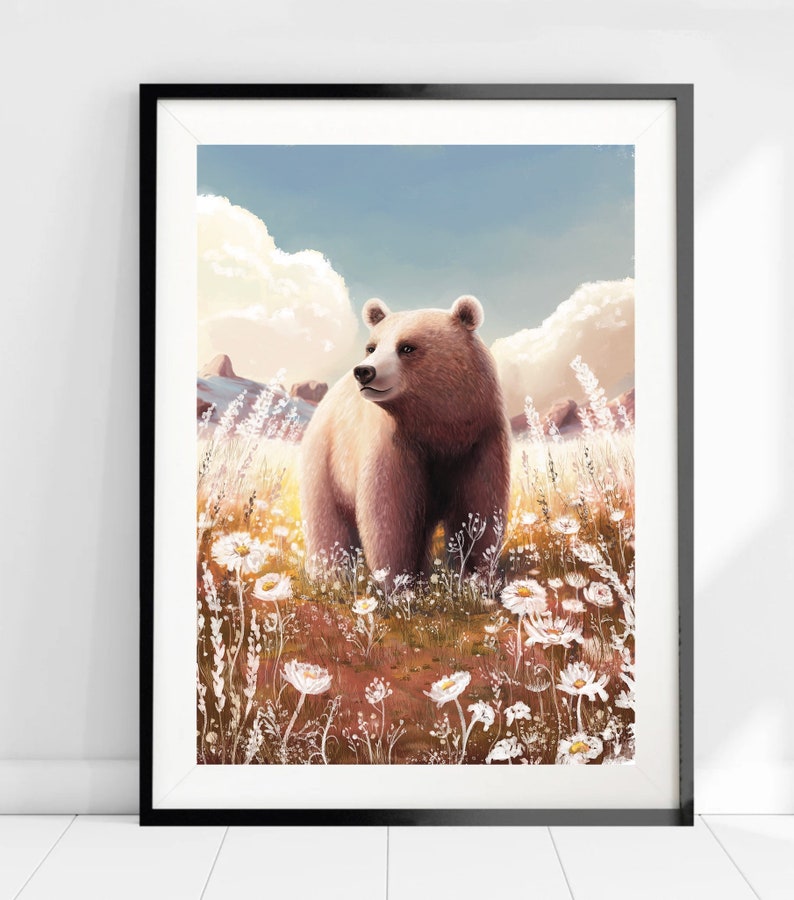 May include: A framed art print featuring a brown bear standing in a field of white wildflowers. The bear is the focal point, set against a backdrop of a blue sky with fluffy clouds. The artwork has a soft, painterly style.