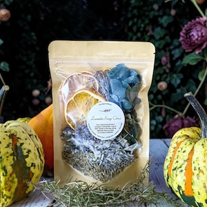 May include: A tan stand-up pouch containing a potpourri blend of dried orange slices, blue eucalyptus leaves, lavender, and rosemary. A circular white label on the front reads Lavender Sage Citrus with instructions for simmering in water.