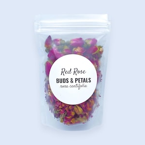 May include: A clear, resealable plastic pouch filled with dried red rose buds and petals. A circular white label on the front features the text Red Rose BUDS & PETALS rosa centifolia in black, stylized lettering against the colorful dried flowers.