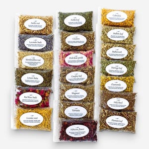 May include: A collection of twenty-one clear plastic pouches containing various dried herbs and flowers, each with a white oval label identifying the contents such as Nettle root, Lavender buds, Pink Rose petals, and Hibiscus flower.