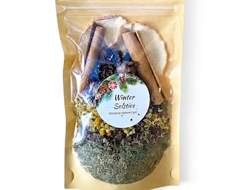 May include: A clear plastic pouch with a brown paper backing containing a stovetop simmer pot mix. The ingredients include dried cinnamon sticks, citrus slices, small pinecones, yellow chamomile flowers, and green herbs. A round label reads Winter Solstice.