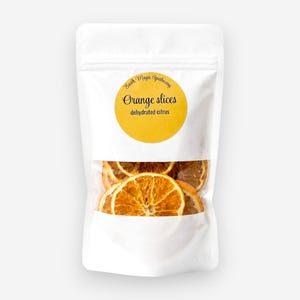 May include: A white stand-up pouch containing dehydrated orange slices. The label features a yellow circle with the text Earth Magic Apothecary, Orange slices, and dehydrated citrus. The contents are visible through a clear window at the bottom.