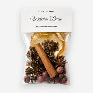 May include: A clear plastic pouch containing a simmer pot blend labeled Earth Fae Magic Witches Brew Intention Simmer Pot Blend. The contents include dried apple slices, a cinnamon stick, star anise, small pinecones, and round berries.