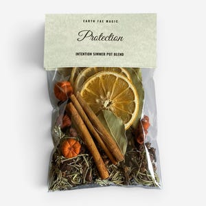 May include: A clear plastic pouch containing a simmer pot blend with dried orange slices, cinnamon sticks, bay leaves, and small orange gourds. The top label reads EARTH FAE MAGIC, Protection, and INTENTION SIMMER POT BLEND in black text.