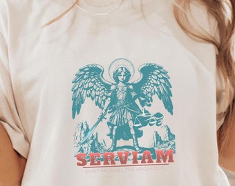 May include: White t-shirt with a blue and white illustration of an angel with wings and a sword. The text "SERVIAM" is printed in red below the image, and the text "SAINT MICHAEL THE ARCHANGEL" is printed in smaller red letters below the word "SERVIAM".