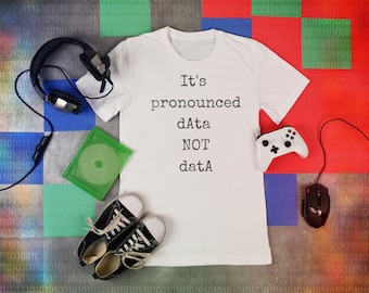 May include: A white t-shirt with the text "It's pronounced dAta NOT datA" on a background of colorful squares with binary code.