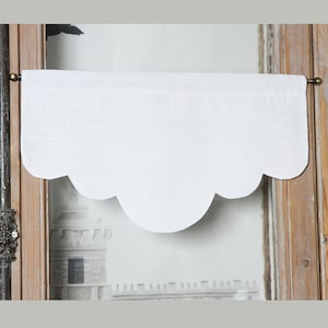 May include: White scalloped valance with a simple design. The valance is made of a lightweight fabric and has a subtle texture.