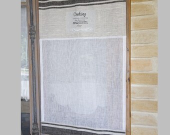 May include: A white linen kitchen curtain with black stripes and a small label that reads "Cooking Original Recipes Daily Breakfast, Lunch & Dinner Open from 7 AM to 10 PM", hanging in a doorway.
