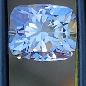 Op de afbeelding: Een heldere, gefacetteerde, rechthoekige edelsteen met een lichtblauwe tint. De edelsteen is gezet in een zilverkleurige zetting.