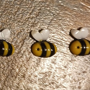 May include: Three small glass bee figurines with black and yellow stripes and white wings.