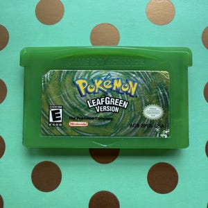May include: A green Game Boy Advance video game cartridge for Pokémon LeafGreen Version. The label features the Pokémon logo, the text LeafGreen Version, an ESRB E rating, the Nintendo logo, and the product code AGB-BPGE-USA on a swirling background.