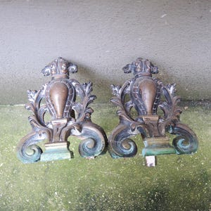 Puede incluir: Un par de fuegos de chimenea de latón antiguo ornamentados con un diseño de desplazamiento y un remate decorativo.