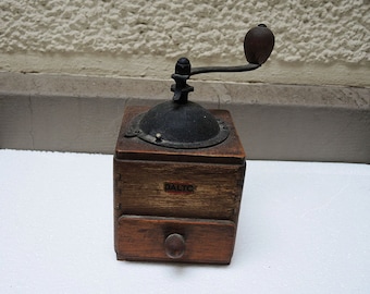 May include: A vintage wooden coffee grinder with a black metal grinding mechanism and a drawer. The grinder has a crank handle and a label that reads "DALTO".